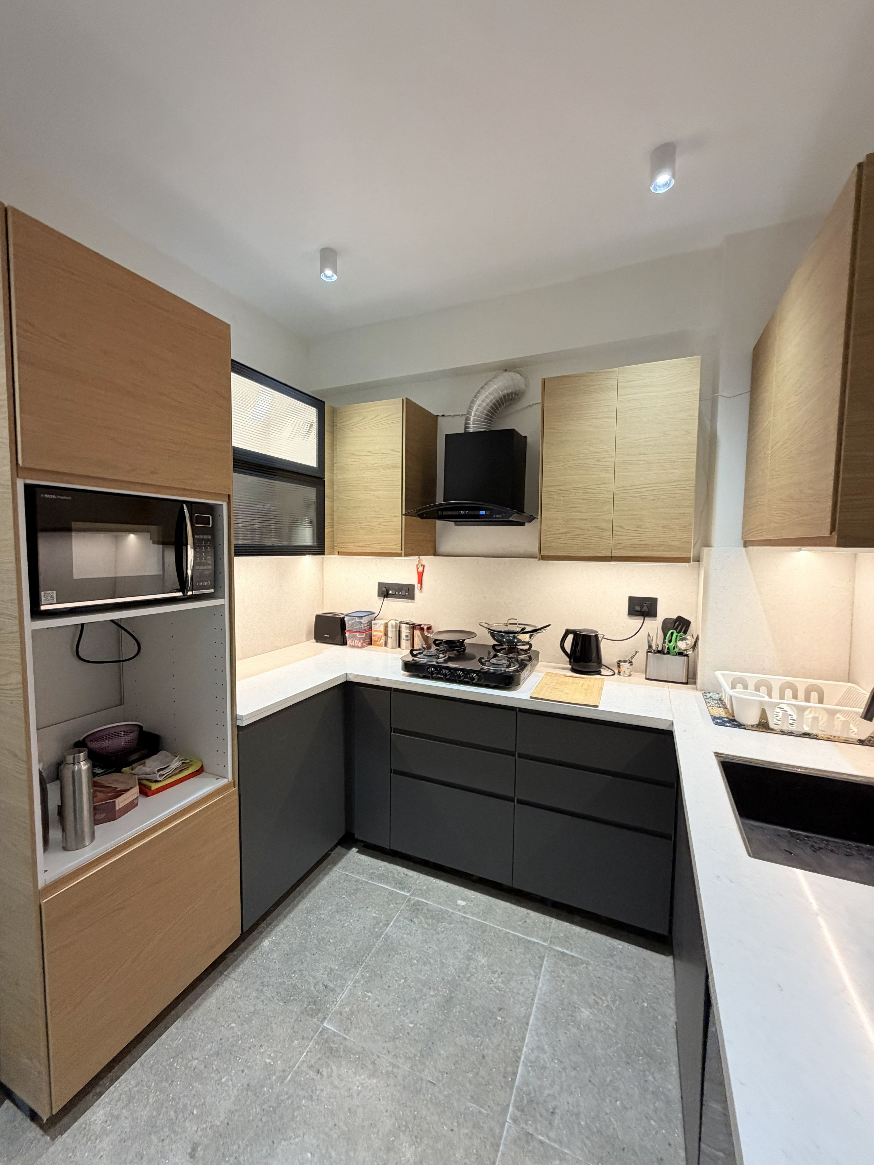 A compact kitchen with built-in appliances, a microwave, a stove, and a ventilation hood.