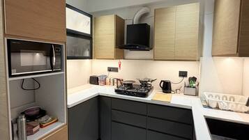 A compact kitchen with built-in appliances, a microwave, a stove, and a ventilation hood.