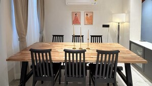 Uma área de refeições moderna com mesa de madeira, cadeiras pretas, ventilador de teto e ar condicionado.