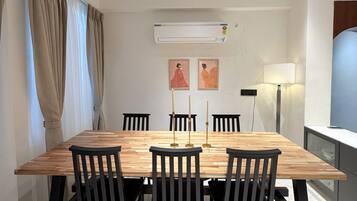 Ein moderner Essbereich mit einem Holztisch, schwarzen Stühlen, einem Deckenventilator und einer Klimaanlage.