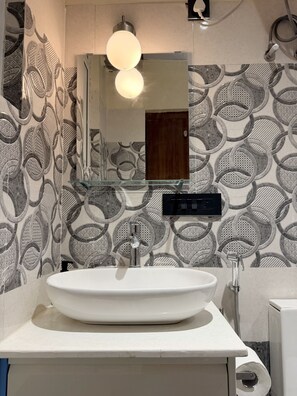 A bathroom with a white sink, a mirror, and a patterned wall. - LiveLikeaHome | Your Spacious 4 BHK Jaipur Home (Jaipur)