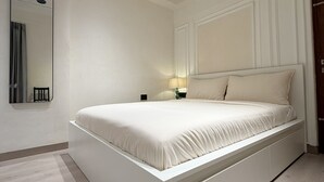 Um quarto moderno com uma cama grande, uma mesa de cabeceira e um espelho.