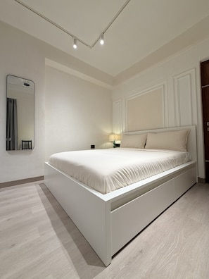 A modern bedroom with a large bed, a bedside table, a nightstand, a mirror, and a door. - LiveLikeaHome | Your Spacious 4 BHK Jaipur Home (Jaipur)