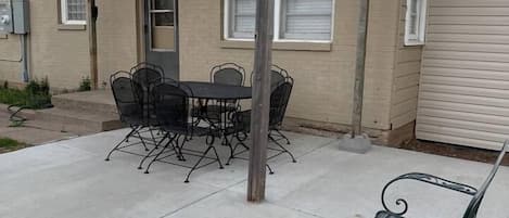 A patio area with a pergola, a dining table with chairs, and a metal bench.