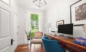 A room with a wooden desk, a computer, a chair, a lamp, and a window with curtains.