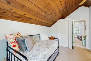 A bedroom with a bed, a wooden ceiling, a white door, and a hallway leading to another room. - Three Bears Cabin | Hot Tub, Pet Friendly, Minutes from Blowing Rock (Blowing Rock)