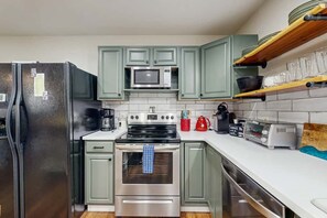 A kitchen with stainless steel appliances, green cabinets, and a white countertop. - Three Bears Cabin | Hot Tub, Pet Friendly, Minutes from Blowing Rock (Blowing Rock)