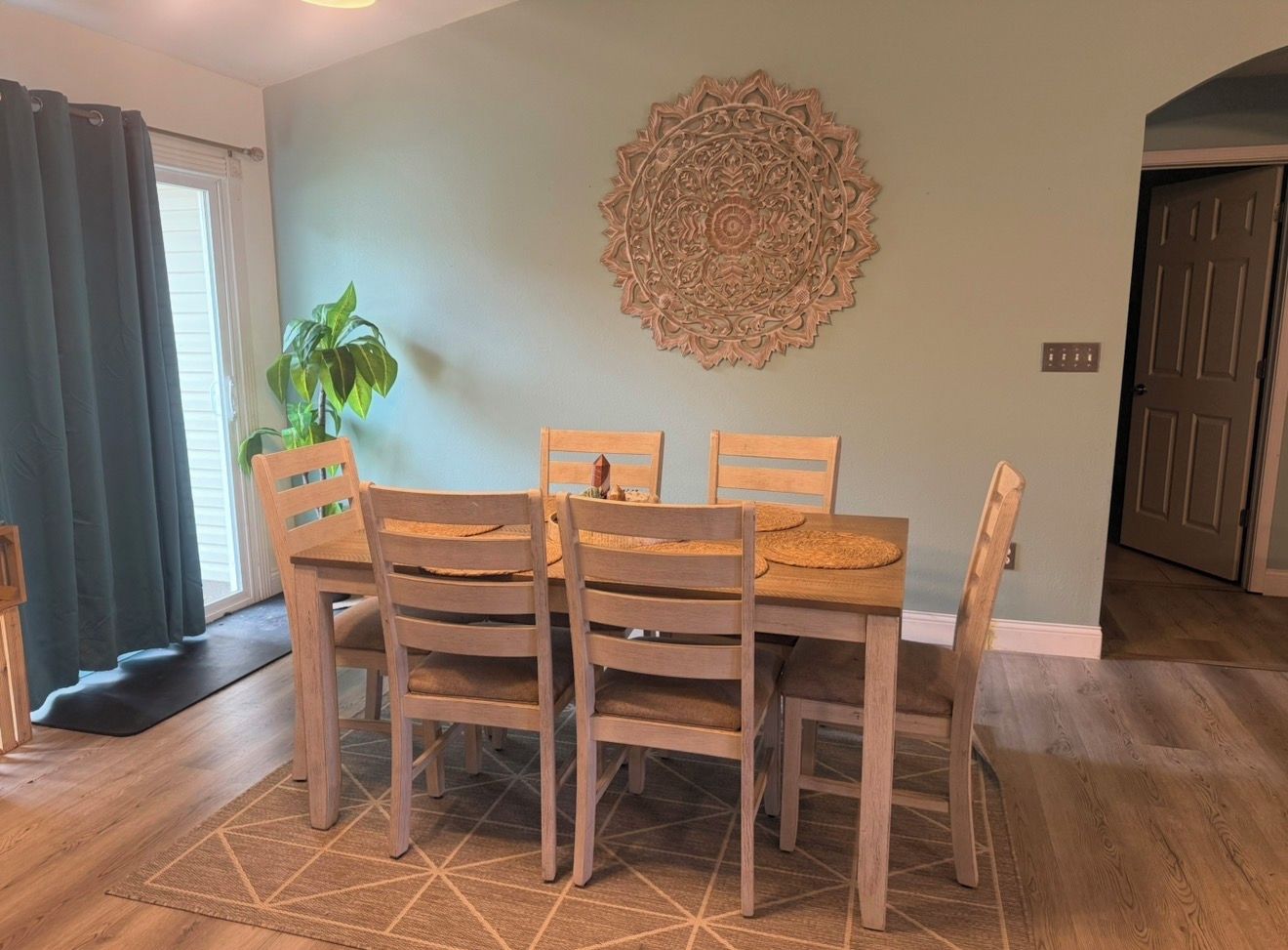 Un coin repas comprenant une table et des chaises, un élément décoratif mural et une plante.