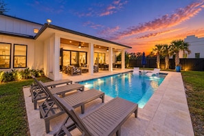 Ein modernes Haus mit Swimmingpool, Sitzgelegenheiten im Freien und einer überdachten Terrasse.