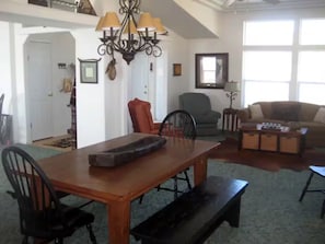 A dining area with a wooden table, chairs, and a bench. There is a chandelier above the table. - 14 Oaks Ranch in Sierra Foothills; perfect for family getaways (Oroville)