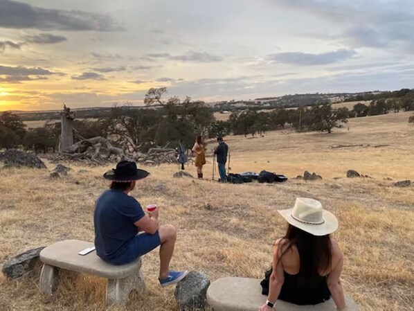 A natural landscape with a sunset, a stone bench, and a person sitting on it. - 14 Oaks Ranch in Sierra Foothills; perfect for family getaways (Oroville)