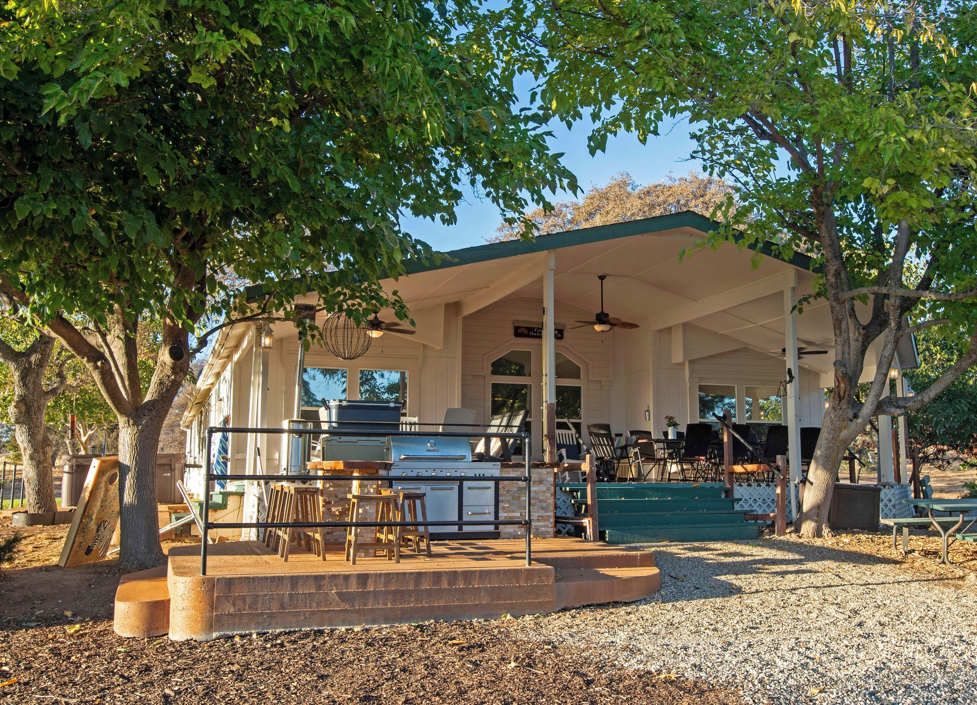 Un área de patio techada al aire libre con una parrilla, asientos y vista a un edificio al fondo.