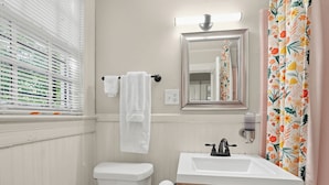 A bathroom with a toilet, sink, mirror, and shower curtain.