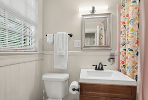A bathroom with a toilet, sink, mirror, and shower curtain.