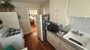 Una cocina compacta con estufa a gas, refrigerador, microondas y pileta.
