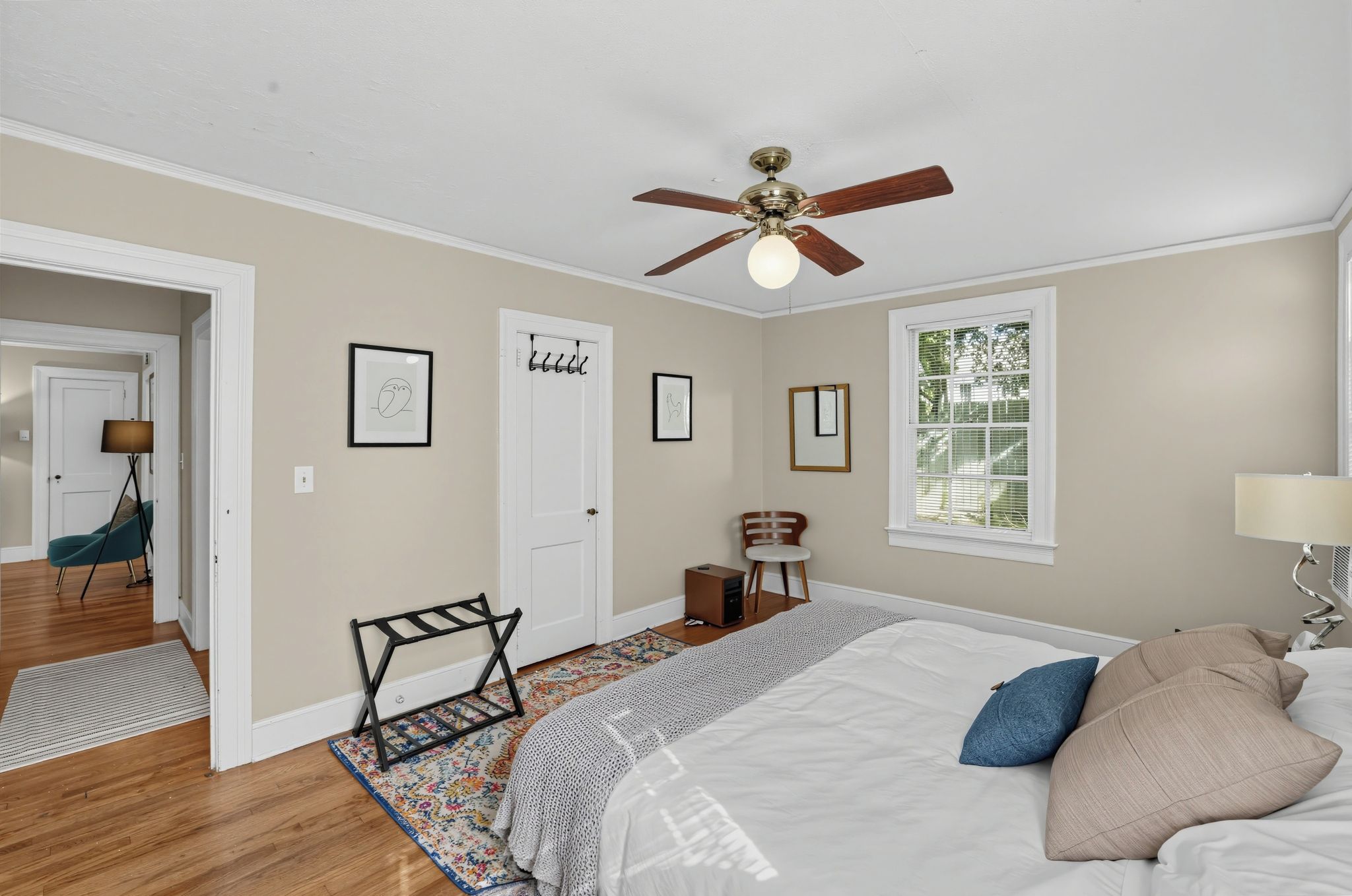 A bedroom with a bed, a ceiling fan, a window, and a door.