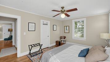 A bedroom with a bed, a ceiling fan, a window, and a door.