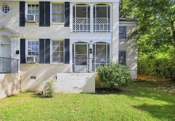 A two-story house with a front porch, a mailbox, and a small garden.