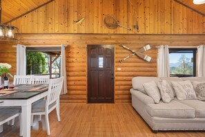 A log cabin interior with a dining area, a sofa, and a door. - Lake and Ski/Gameroom/Dogrun (Wofford Heights)