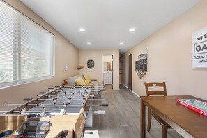 Ein Zimmer mit einem Kicker, einer Dartscheibe und einem Monopoly-Spiel.