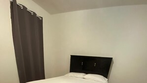 A neatly made bed with a dark headboard in a room with wooden flooring and a striped rug. - Private room near NYC! (Paterson)