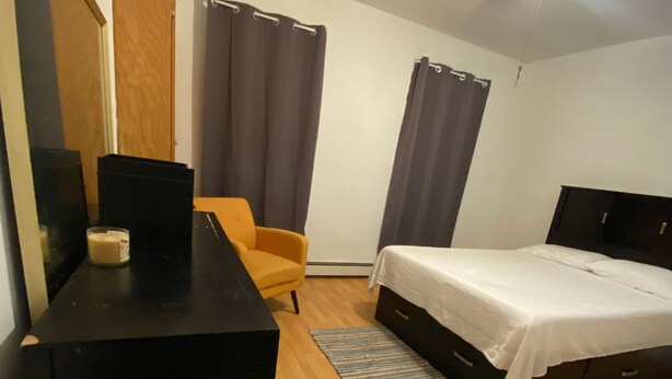 A bedroom with a bed, a desk, a chair, a ceiling fan, and a window with curtains. - Private room near NYC! (Paterson)