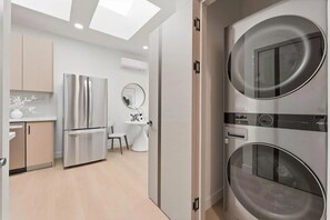 A modern kitchen with stainless steel appliances, a dining area with a round table, and a built-in washer and dryer unit.