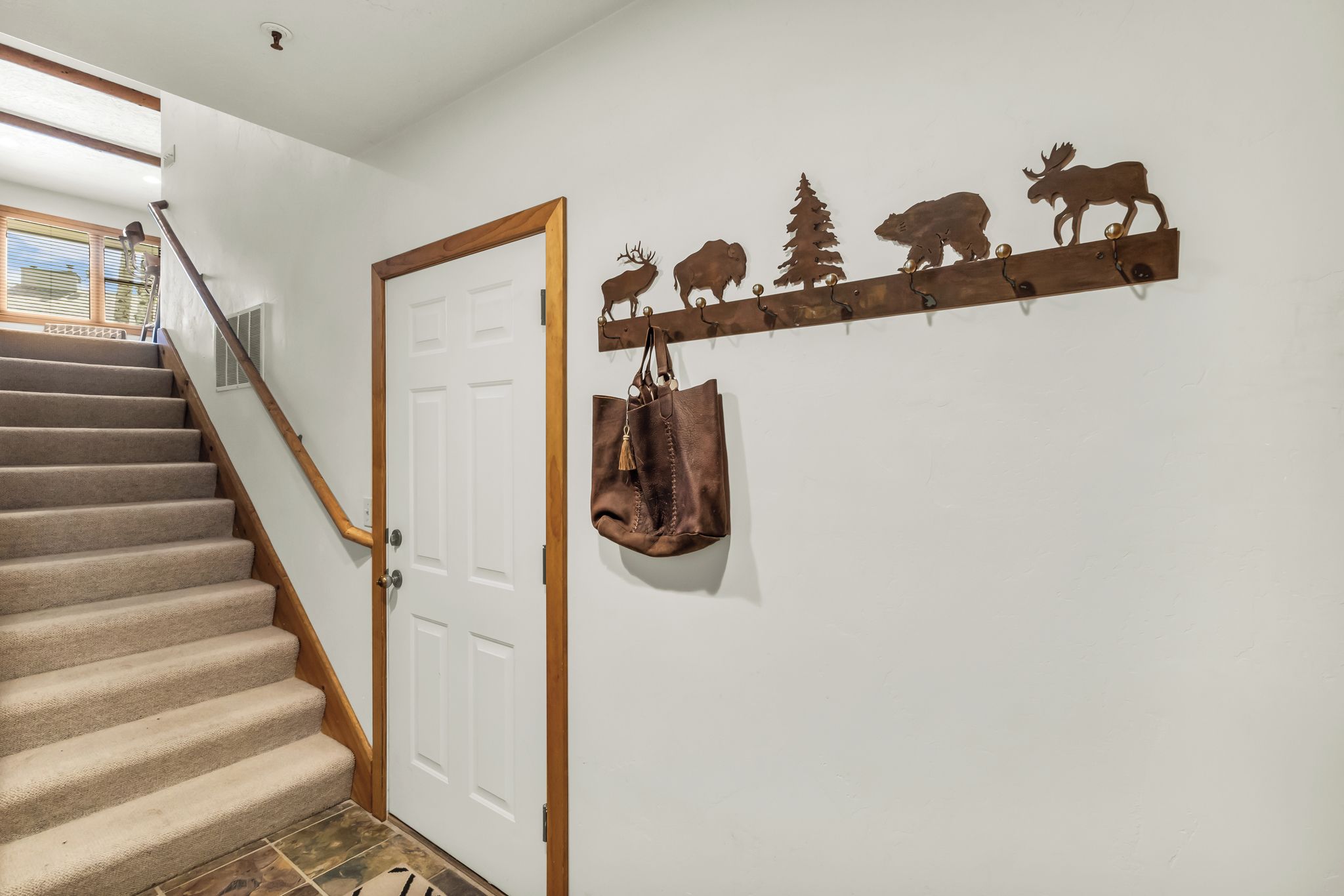 A staircase with carpeted steps and wooden handrails, leading to a white door.