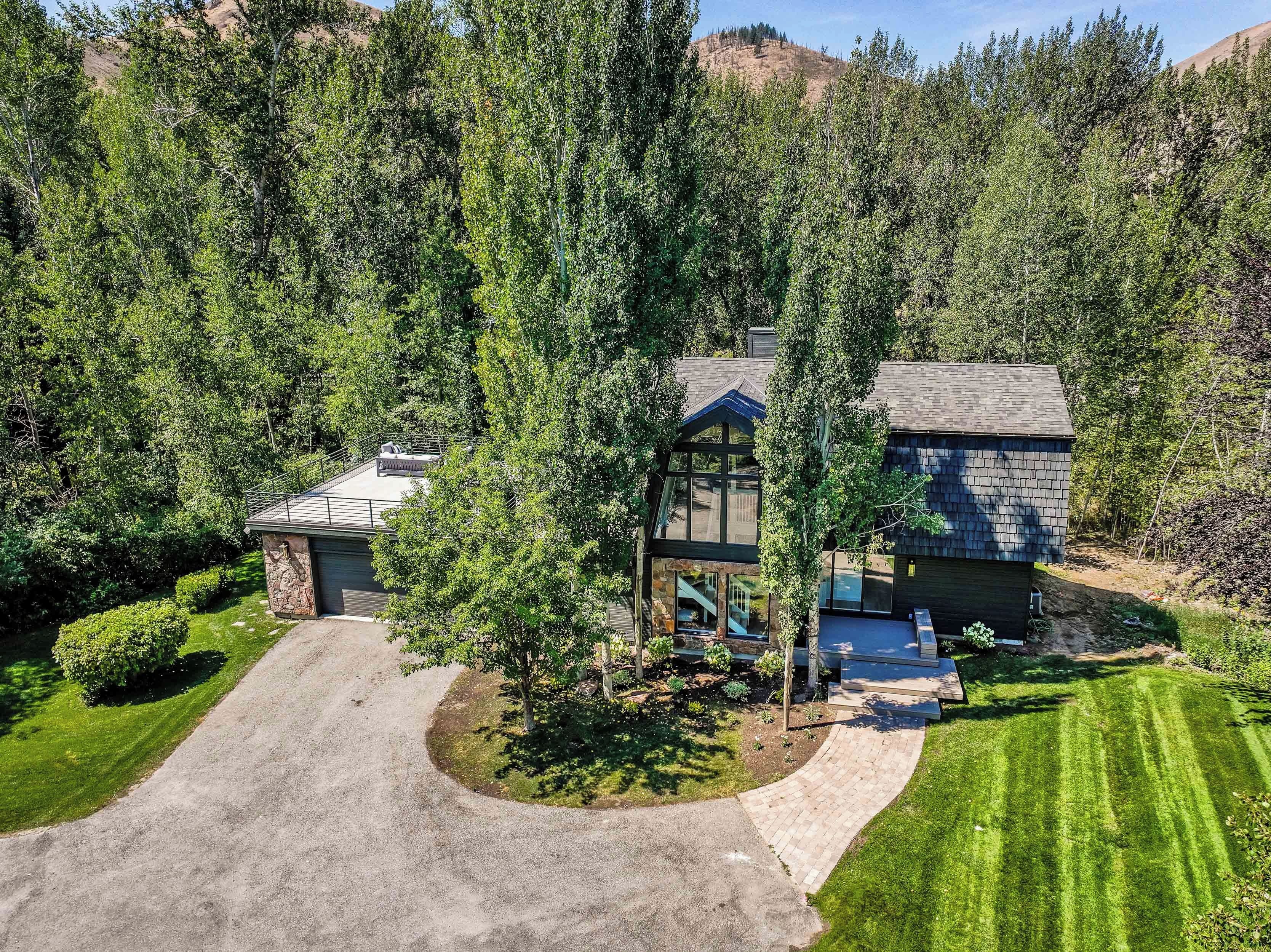 A two-story house with a stone foundation, a covered patio, and a driveway leading to a garage.
