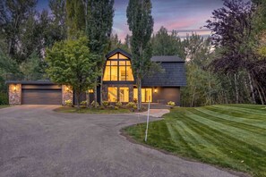 Een modern herenhuis met twee verdiepingen, een gevel van natuursteen, grote ramen en een verzorgd gazon.