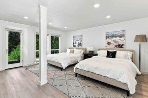 Quarto moderno com duas camas, uma janela grande e vista para uma paisagem nevada.