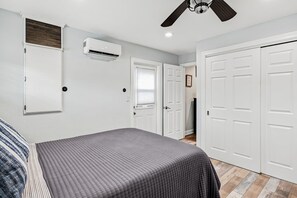 A bedroom with a bed, a ceiling fan, an air conditioning unit, and white doors. - 🐢Turtle Oasis | 4BR/ 2.5 bath | Largo retreat with pool and hot tub| Sleeps 8 (Largo)