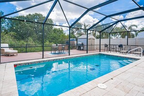 A swimming pool with a covered area, surrounded by outdoor furniture and a view of trees. - 🐢Turtle Oasis | 4BR/ 2.5 bath | Largo retreat with pool and hot tub| Sleeps 8 (Largo)