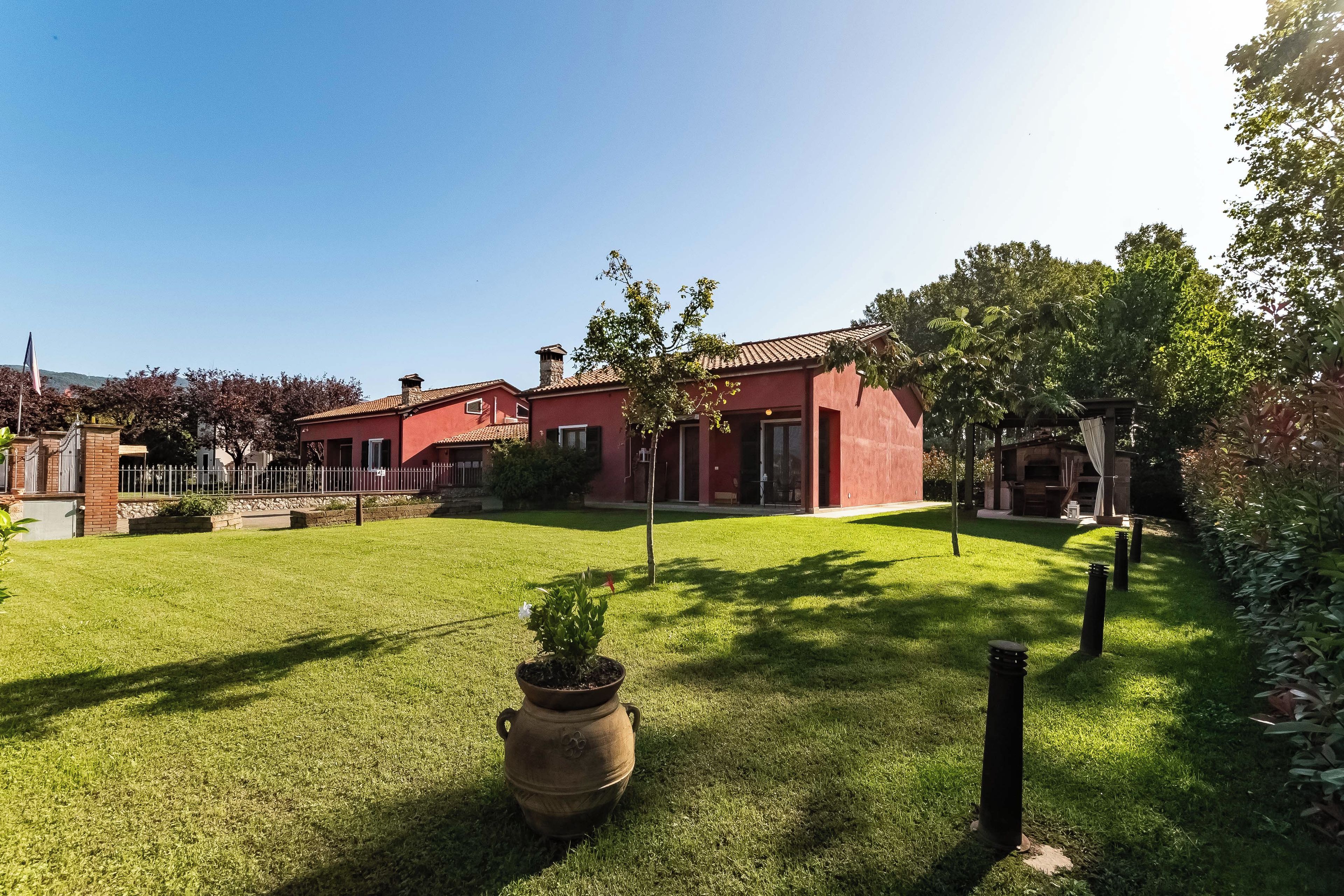 A red building with a well-maintained lawn and a large pot in the foreground.