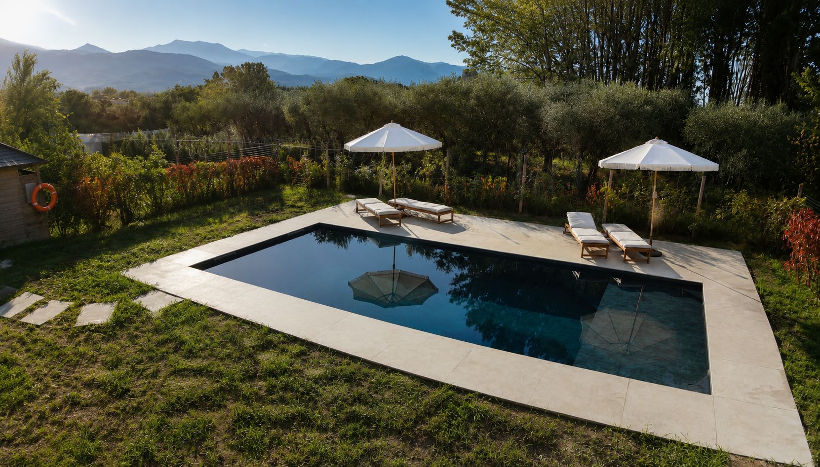 Une piscine rectangulaire avec deux parasols blancs et des chaises longues.