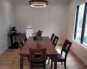 A dining room with a rectangular table, six chairs, a vase with flowers, and a ceiling light fixture. - Beautiful spacious 5 bedroom on half an acre, with pool and tons of amenities. (Dallas)