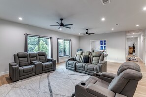 A spacious living room with a large window, ceiling fans, and a sectional sofa. - Beautiful spacious 5 bedroom on half an acre, with pool and tons of amenities. (Dallas)