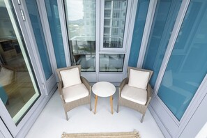 A balcony with two wicker chairs and a small round table, overlooking a cityscape. - Luxury condo with so many amenities! (Kelowna)