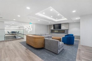 A modern lobby with a seating area, a fireplace, and a staircase leading to an upper level. - Luxury condo with so many amenities! (Kelowna)