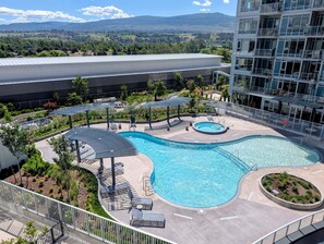 Ein Dachpool mit Liegestühlen und Sonnenschirmen, umgeben von Grün und mit Blick auf entfernte Berge.