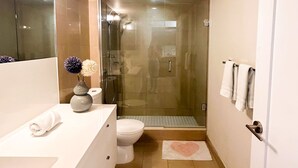 A modern bathroom with a glass-enclosed shower, a white sink, and a toilet. - StayToronto - CN Tower & Front St Suites (Toronto)