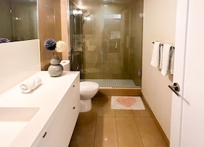 Casa de banho moderna com cabine de duche em vidro, lavatório branco e sanita.