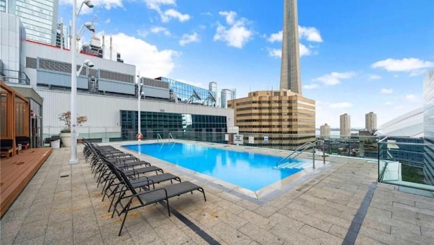 A rooftop pool with sun loungers, surrounded by modern buildings and a clear sky. - StayToronto - CN Tower & Front St Suites (Toronto)