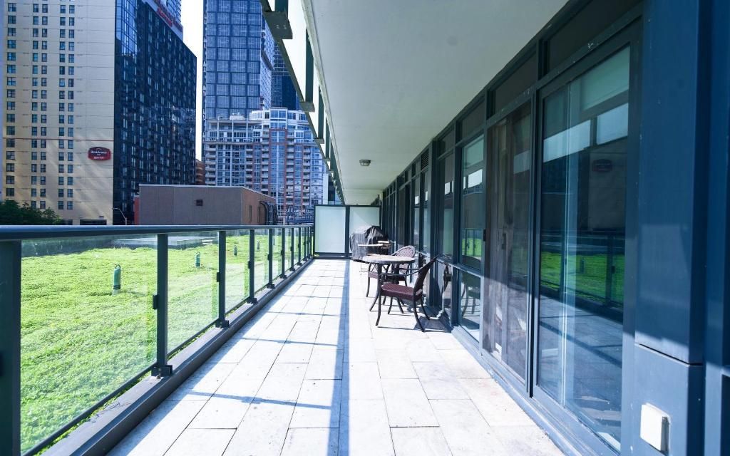 A balcony with a view of a cityscape, a table with chairs, and a grassy area.