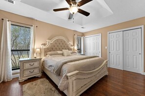 A bedroom with a large bed, a nightstand, a ceiling fan, and two doors. - The Grand Mulligan at Pointe Royale Golf Club/Pools-Tennis-Pickleball-Gym (Branson)