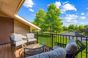 A balcony with outdoor furniture, a glass table, and a view of a residential street and greenery. - The Grand Mulligan at Pointe Royale Golf Club/Pools-Tennis-Pickleball-Gym (Branson)