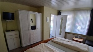A hotel room with a bed, a wardrobe, a television, and a window with curtains. - Vrbo Property (Winterberg/Züschen)