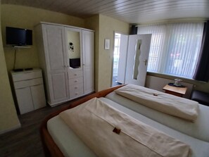 Une chambre d’hôtel avec un lit, une armoire, une télévision et une fenêtre avec des rideaux.
