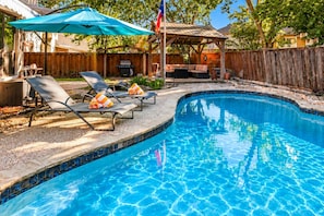 A swimming pool with lounge chairs and a covered patio area. - Family Friendly Retreat, Fire Pit, Games, More (McKinney)