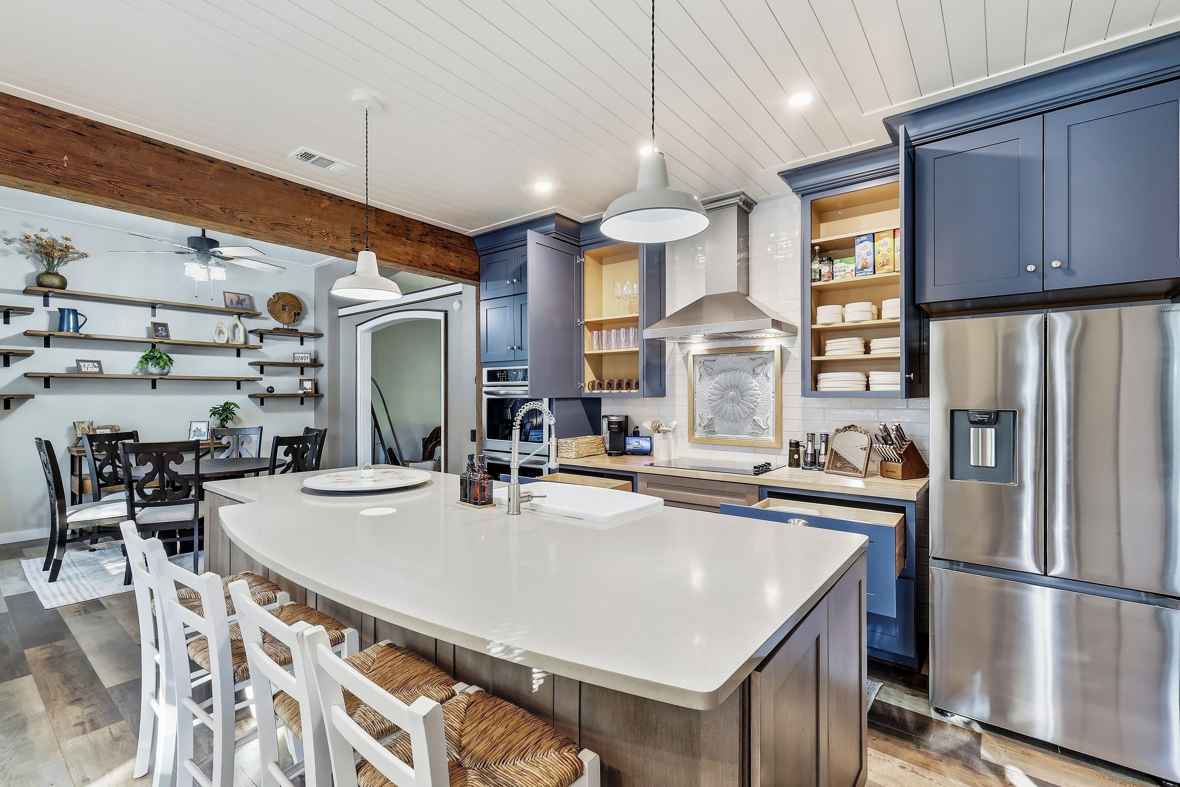 A modern kitchen with a central island, stainless steel appliances, and built-in cabinetry.